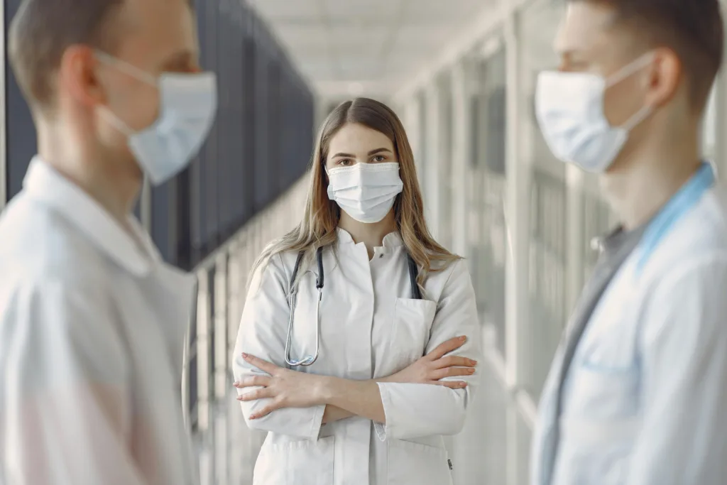 Groupe de médecins dans un couloir, portant des masques et des blouses blanches, symbolisant les professionnels libéraux en société d’exercice libéral (SEL).